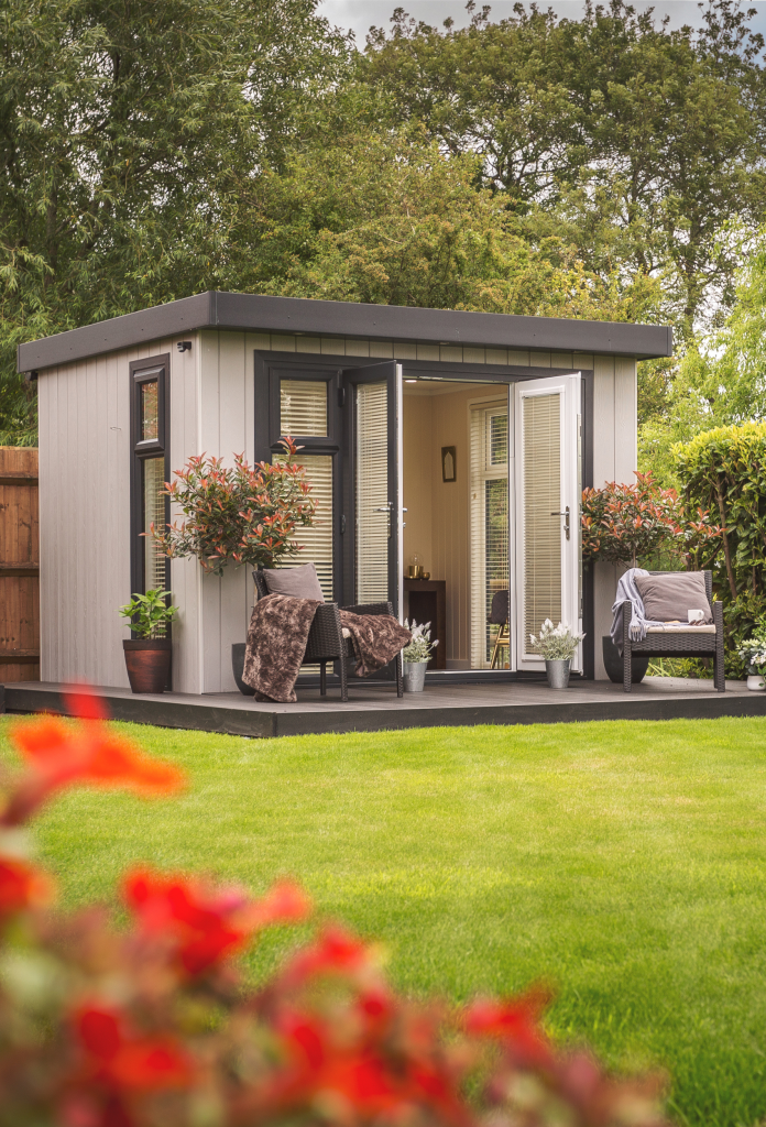 cream garden room building in garden with flowers in front of it